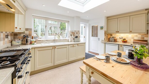 A modern kitchen with a skylight, a large island, and a dining area.