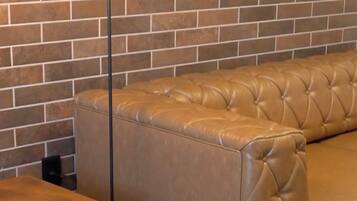 Una sala de estar moderna con un sofá de cuero, una mesa de madera y una lámpara de pie frente a una pared de ladrillo.