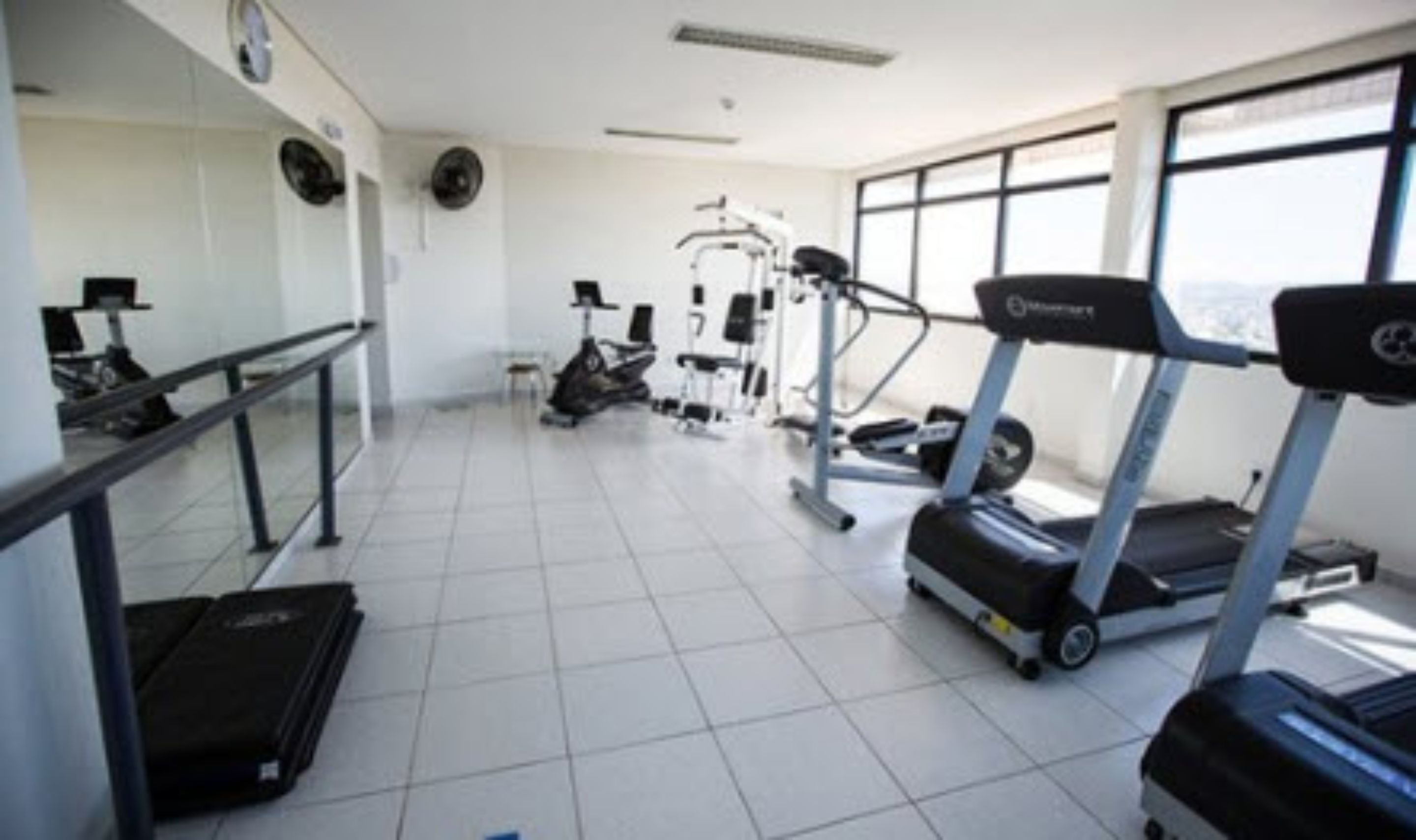 Un gimnasio con cintas de correr, elípticas y bancos de pesas.