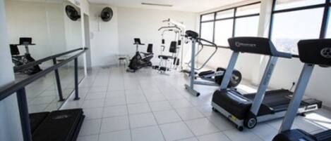 Un gimnasio con cintas de correr, elípticas y bancos de pesas.