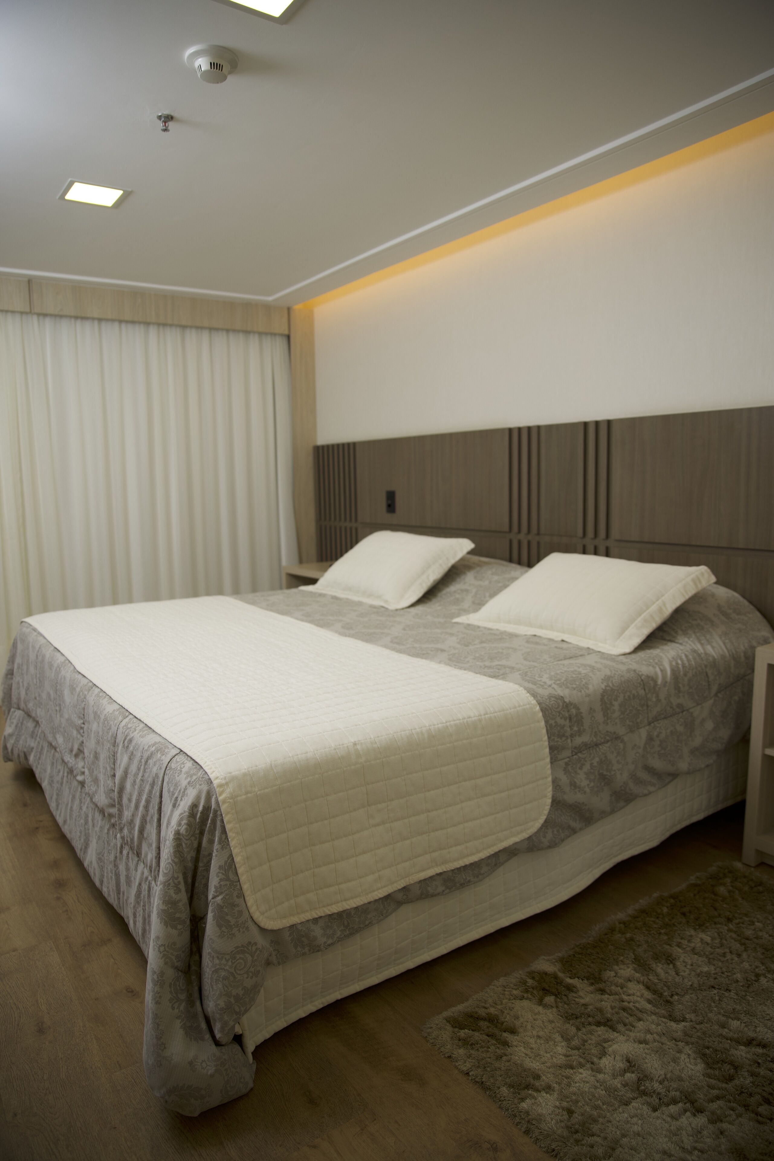 A modern bedroom with a large bed, a nightstand, a bedside table, and a headboard.