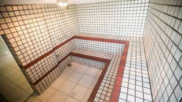 Bathroom features a tiled floor and walls with a grid pattern and a central bathing area.