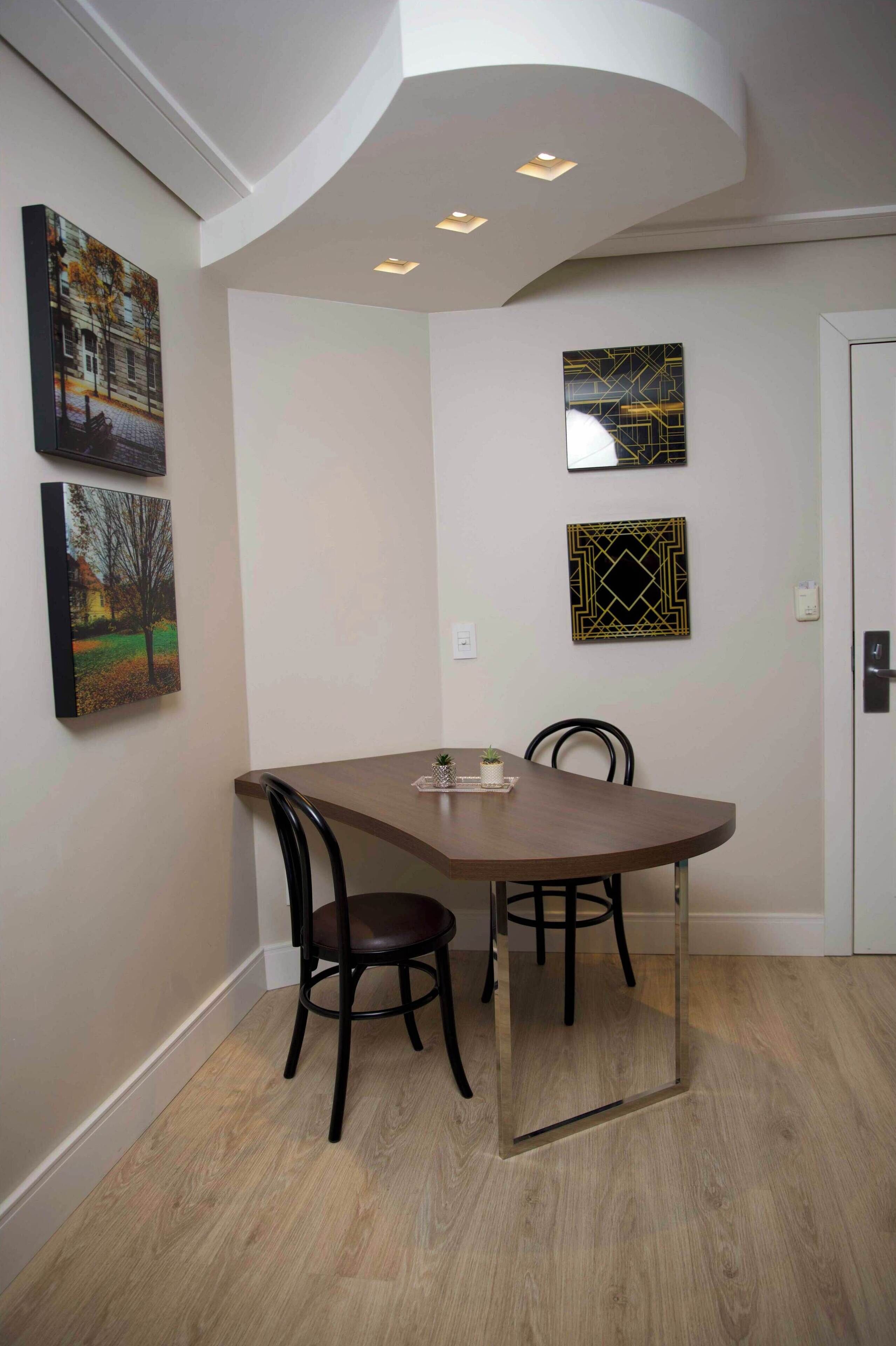 A dining area with a round table, two chairs, and wall-mounted artwork.