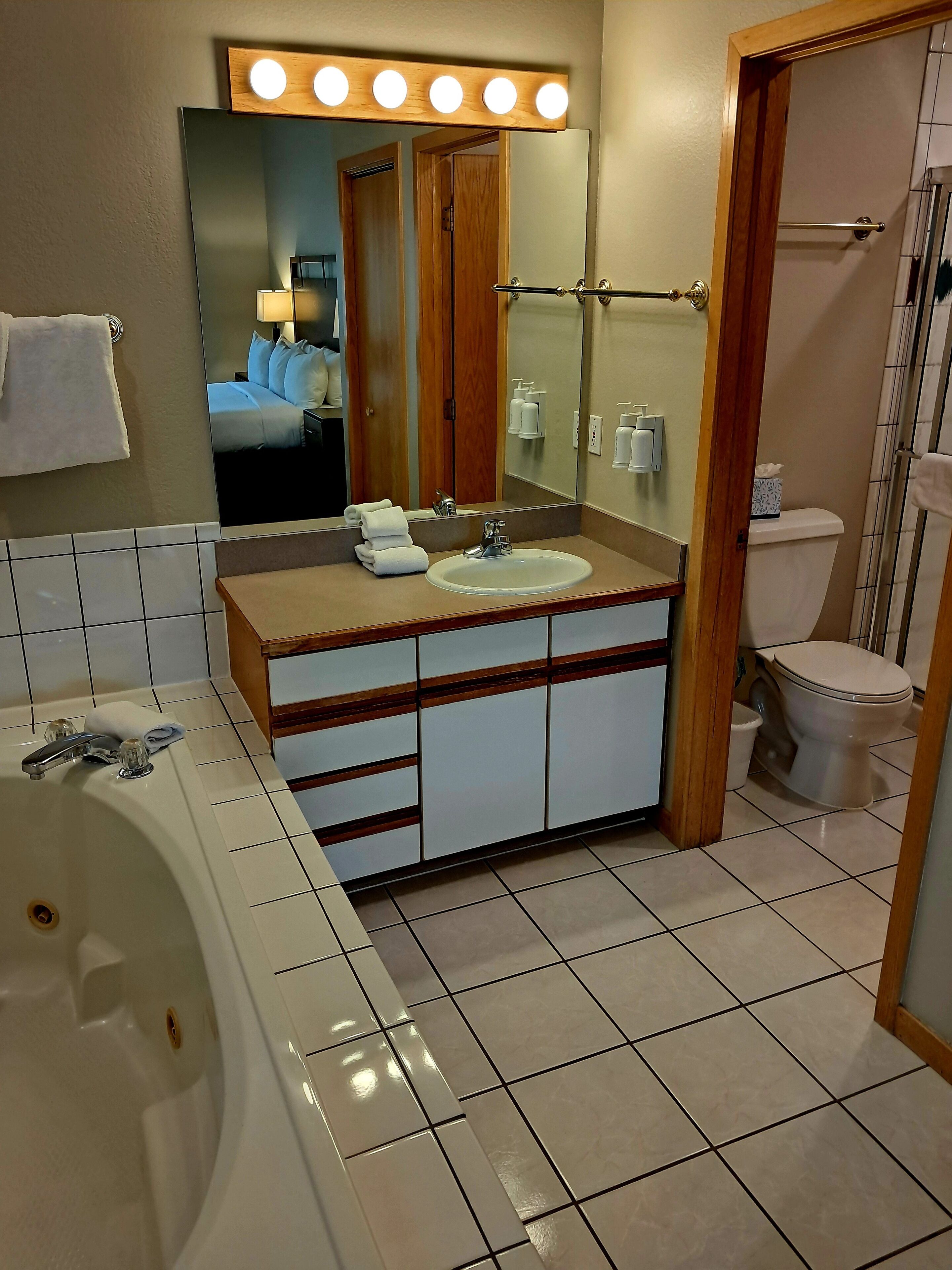 A bathroom with a bathtub, sink, mirror, and toilet.