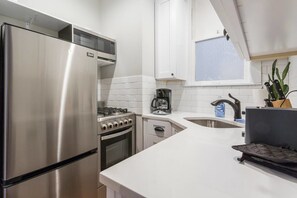 A modern kitchen with stainless steel appliances, a gas stove, a coffee maker, and a sink. - Windy City Wanderer - Depaul, Train, Wrigley Field (Chicago)