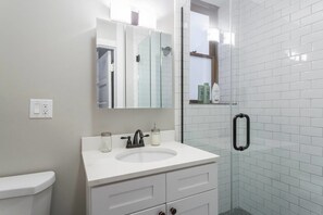 A modern bathroom with a white sink, a glass shower enclosure, and a mirror above the sink. - Windy City Wanderer - Depaul, Train, Wrigley Field (Chicago)