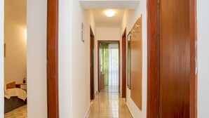 Un couloir avec des portes en bois, un sol carrelé et un luminaire au plafond.
