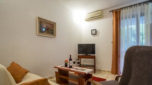 Un salon avec un canapé, une table basse en bois, un téléviseur et une fenêtre avec des rideaux.