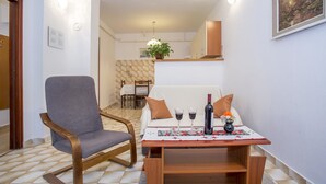 Un coin repas avec une table dressée pour deux personnes, une chaise et une bouteille de vin.