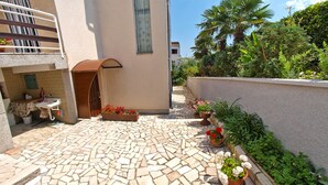 Une cour avec un sol carrelé, une petite table, un évier et des plantes en pot.