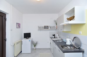 Une cuisine compacte équipée d’un réfrigérateur, d’un lave-linge, d’une cuisinière et d’un petit téléviseur.