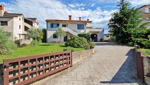 Zona residencial con un sendero pavimentado que lleva a una casa con techo inclinado y una antena parabólica.