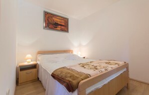 Une chambre à coucher avec un lit en bois, une table de chevet avec une lampe et un tableau accroché au mur.
