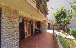 Un bâtiment en pierre doté d’un patio, d’une table et de chaises.