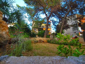 Une cour bordée de murs en pierre, une pelouse et un bâtiment doté de balcons.
