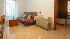 A living room with a sofa, a small table, a heater, and a wooden wardrobe. - Apartment 397 (Pula)