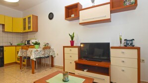 A compact living space with a kitchen, dining area, and a TV on a wooden stand. - Apartment 397 (Pula)