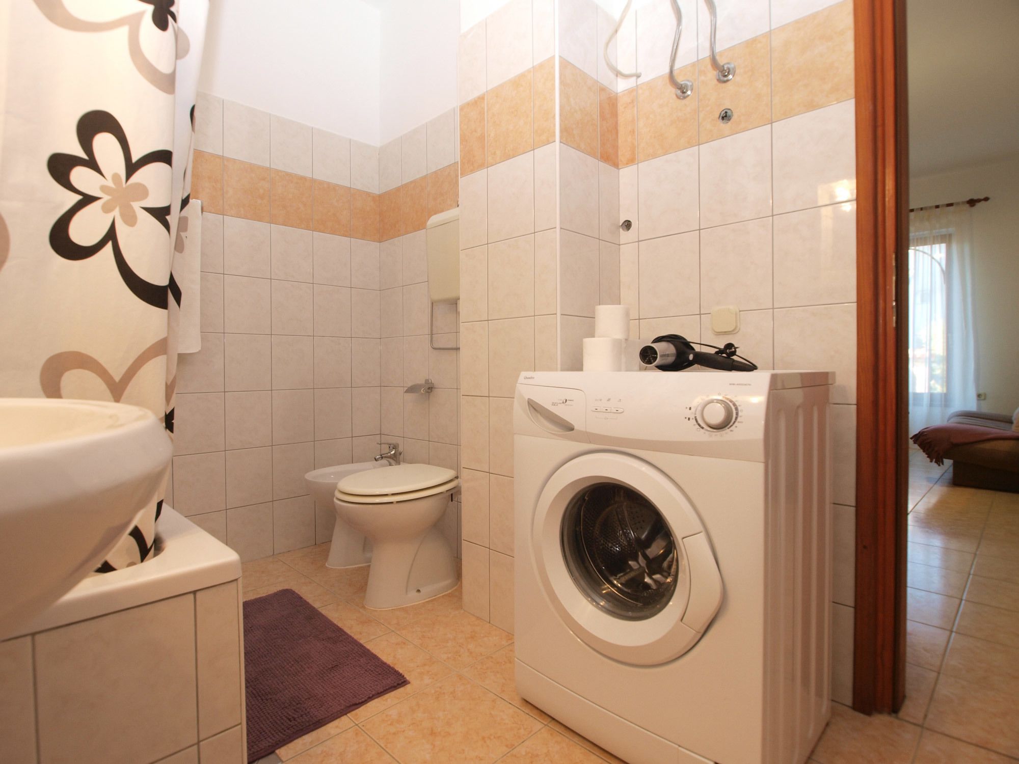 A compact bathroom with a toilet, washing machine, and sink.