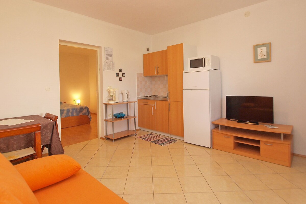 Un espacio habitable compacto con kitchenette, zona de comedor y de estar.