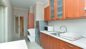 A modern kitchen with wooden cabinets, a microwave, a refrigerator, and a sink. - Apartment 38 (Fazana)