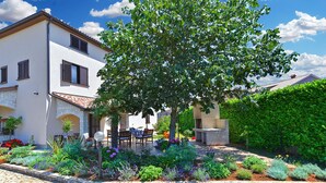 A two-story house with a garden in front, stone paving, and a patio with outdoor furniture. - Apartment 38 (Fazana)