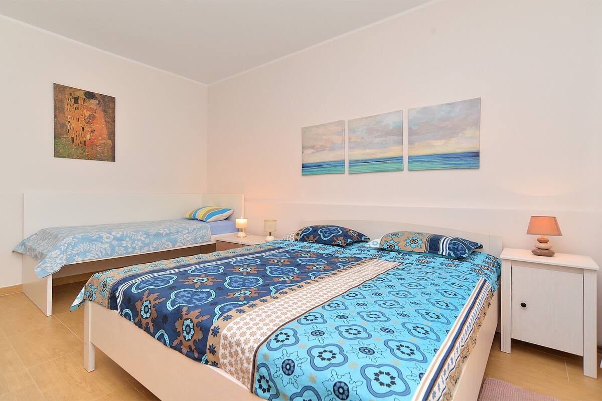 Quarto com duas camas, mesa de cabeceira e obras de arte nas paredes.