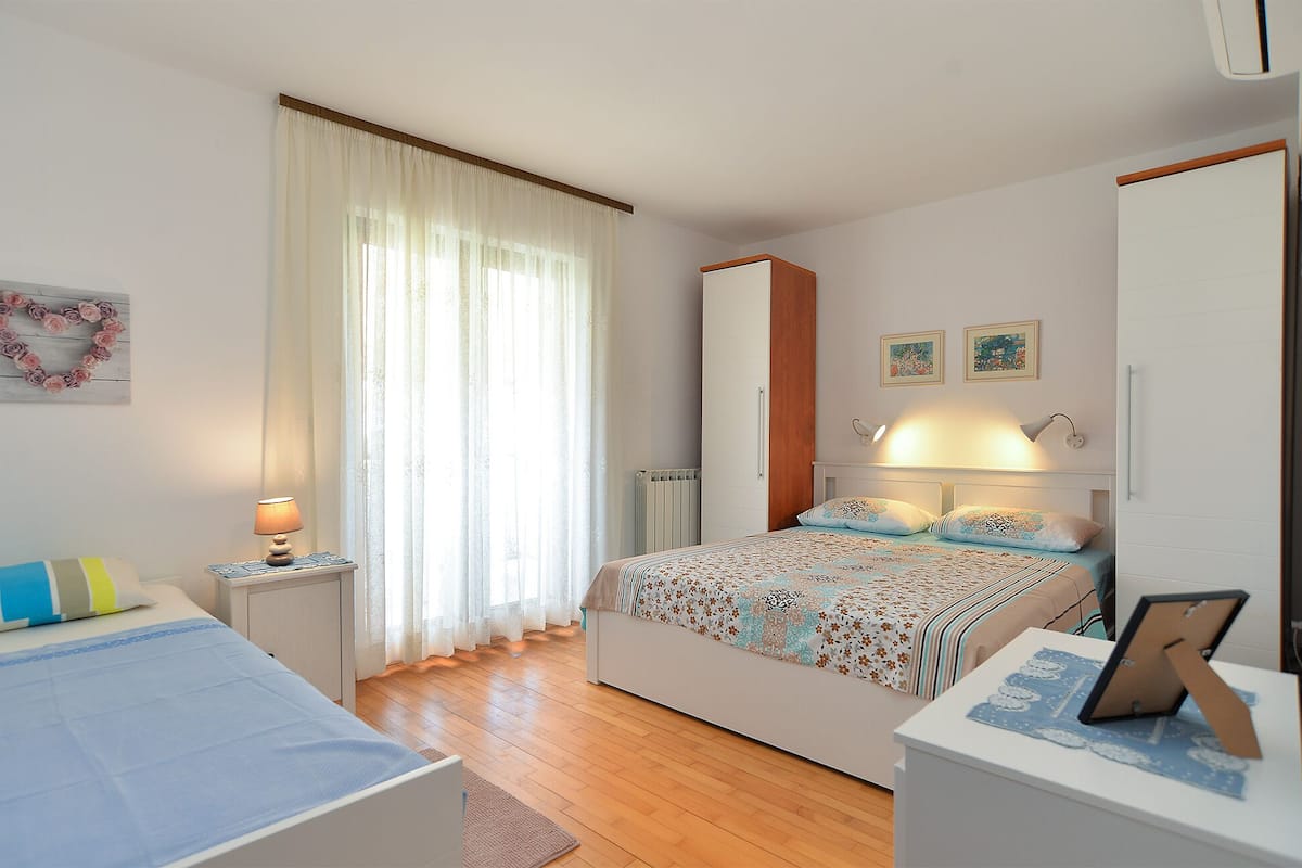 Quarto com cama, mesa de cabeceira, abajur e cômoda.