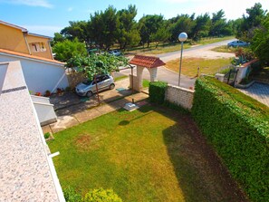 A residential area with a paved driveway, a parked car, and a small brick structure.
