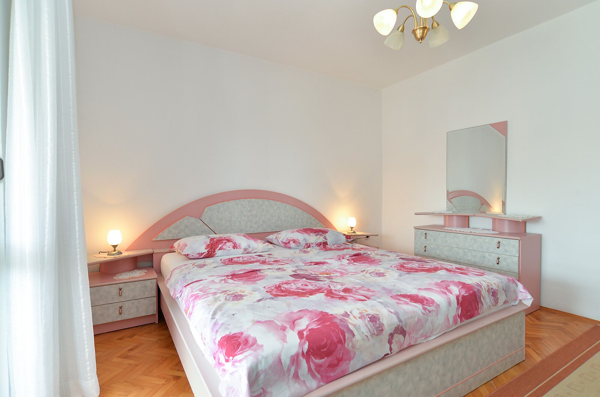 Ein Schlafzimmer mit Bett, Nachttischen, einem Schminktisch und einem Spiegel.