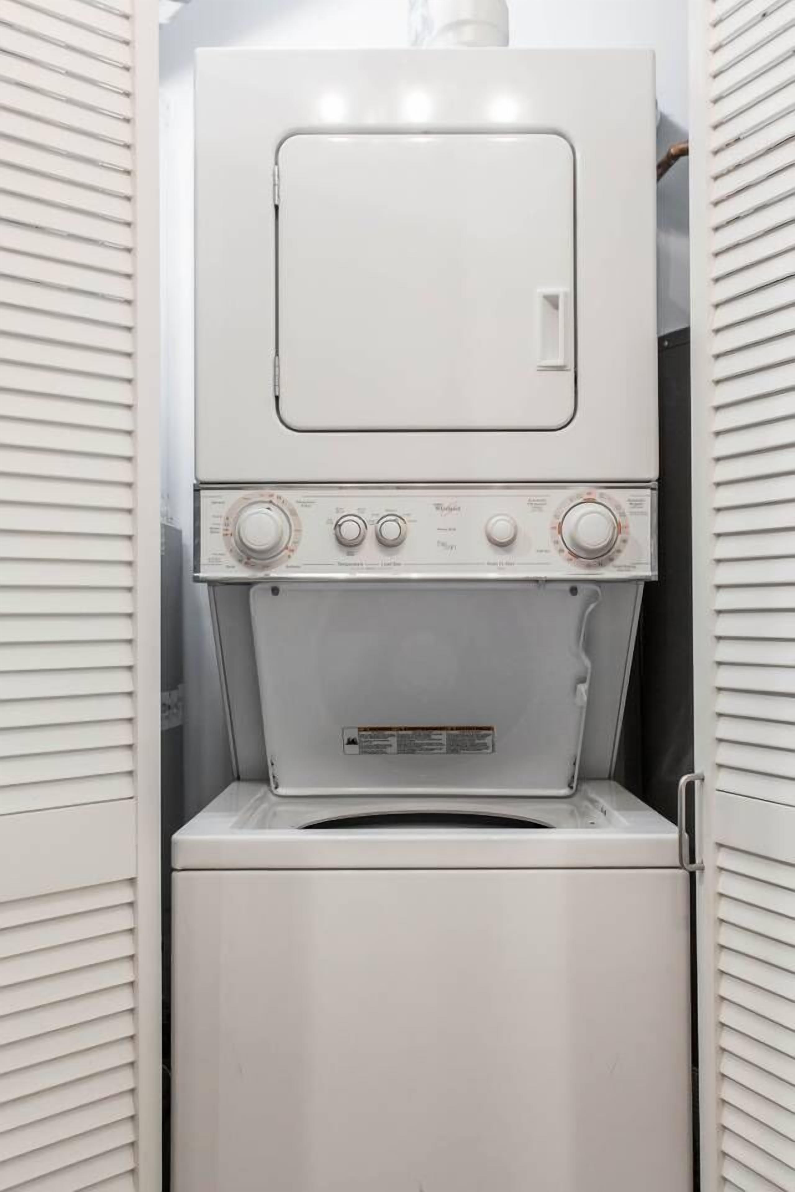 A compact, white, wall-mounted washer and dryer unit with a control panel featuring multiple dials and a small display.