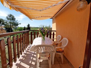 Un balcon avec une table, des chaises et un parasol à rayures.