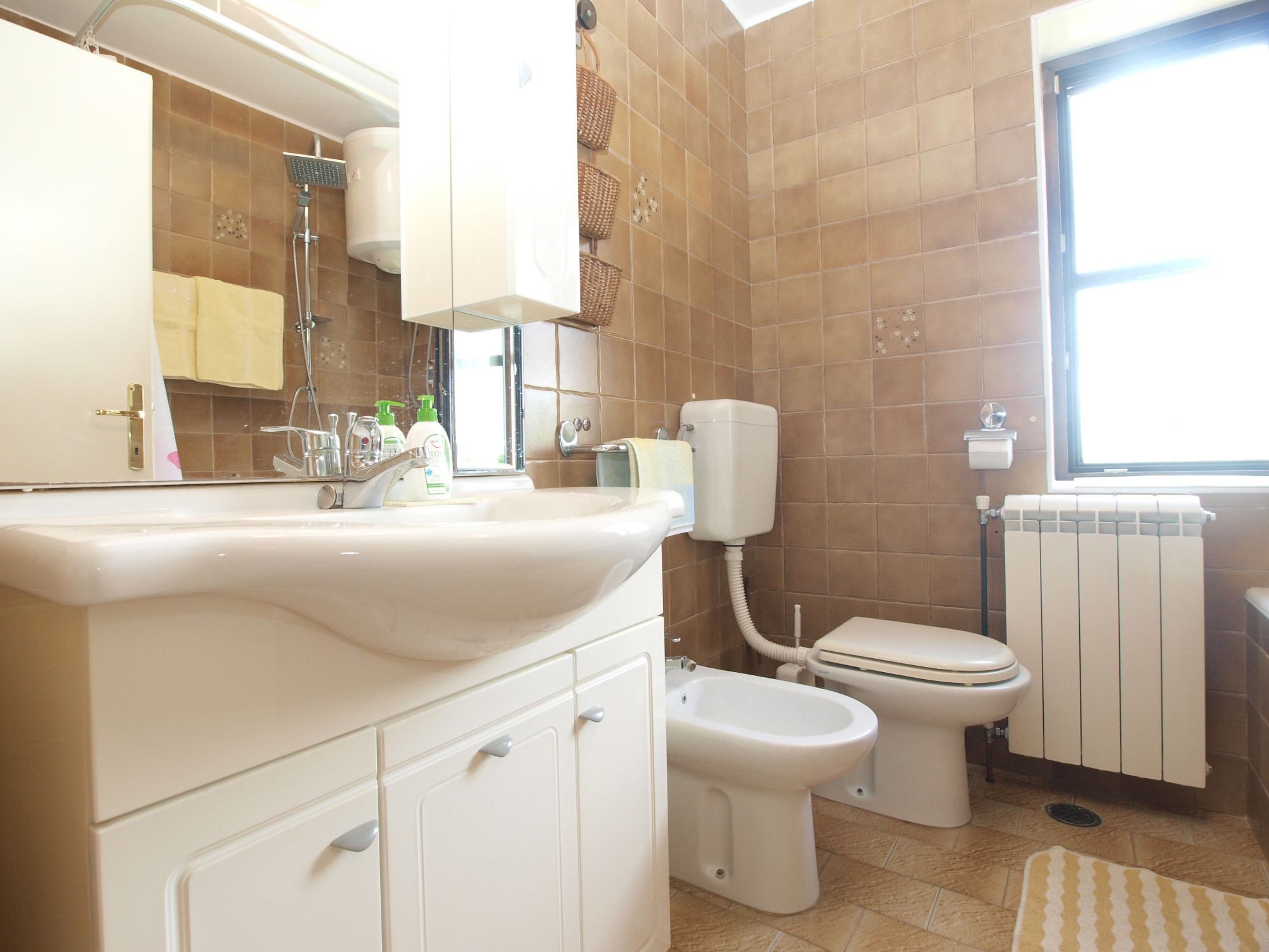 Un baño con lavamanos, inodoro, bidé y ventana.