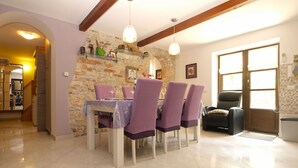 A dining area with a stone wall, a wooden ceiling, and a dining table set for four. - Apartment 64 (Vodnjan)
