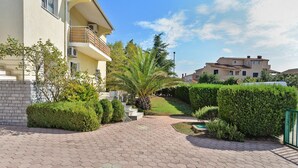 A residential building with a paved walkway, a palm tree, and well-maintained hedges. - Apartment 72 (Pula)