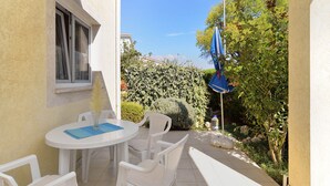 An outdoor patio with a round table and four chairs, a window, and a blue umbrella. - Apartment 72 (Pula)