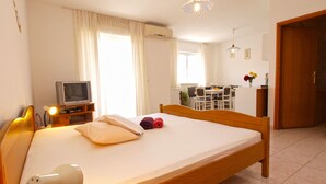 A hotel room with a bed, a TV, a desk, and a dining area. - Apartment 72 (Pula)