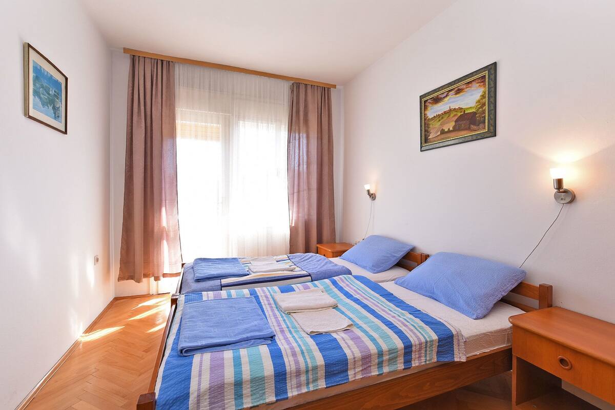 A room with a large bed, two bedside tables, a wall-mounted lamp, and a painting.