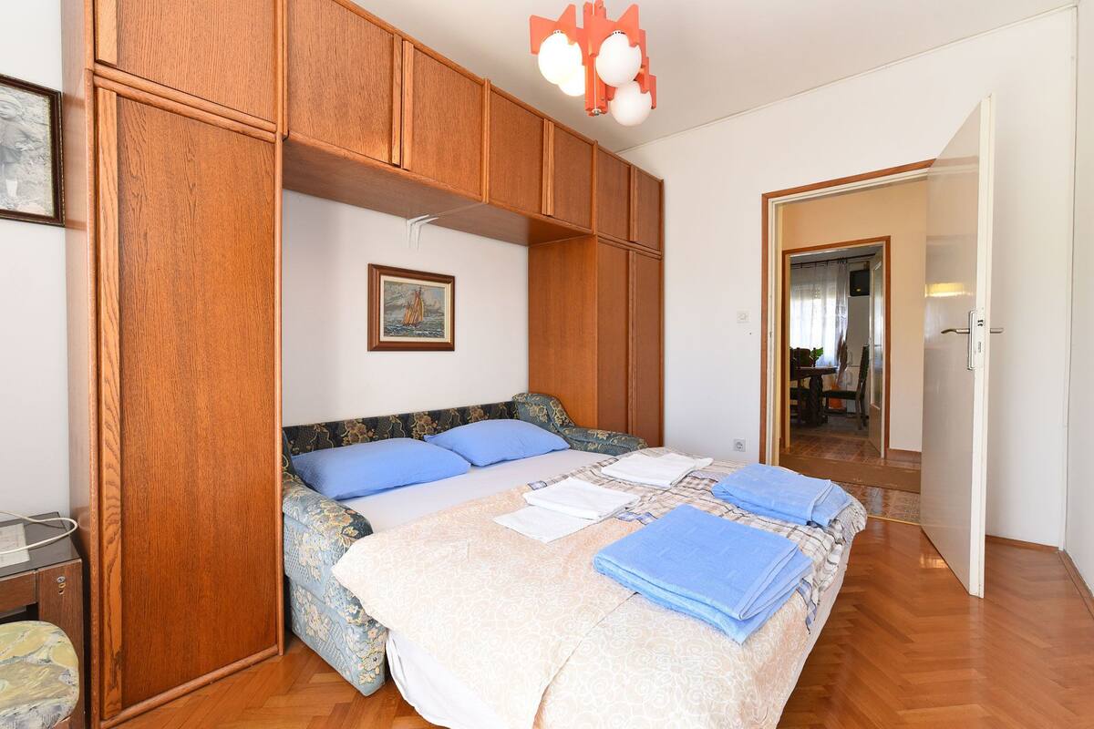A bedroom with a bed, wooden wardrobe, and a painting on the wall.