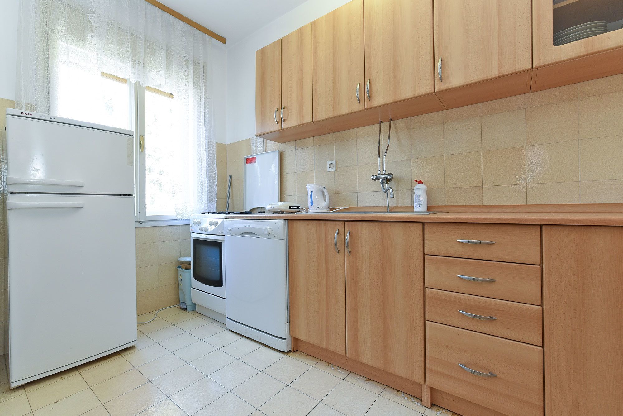 A kitchen with wooden cabinets, a white refrigerator, a stove, and a sink.