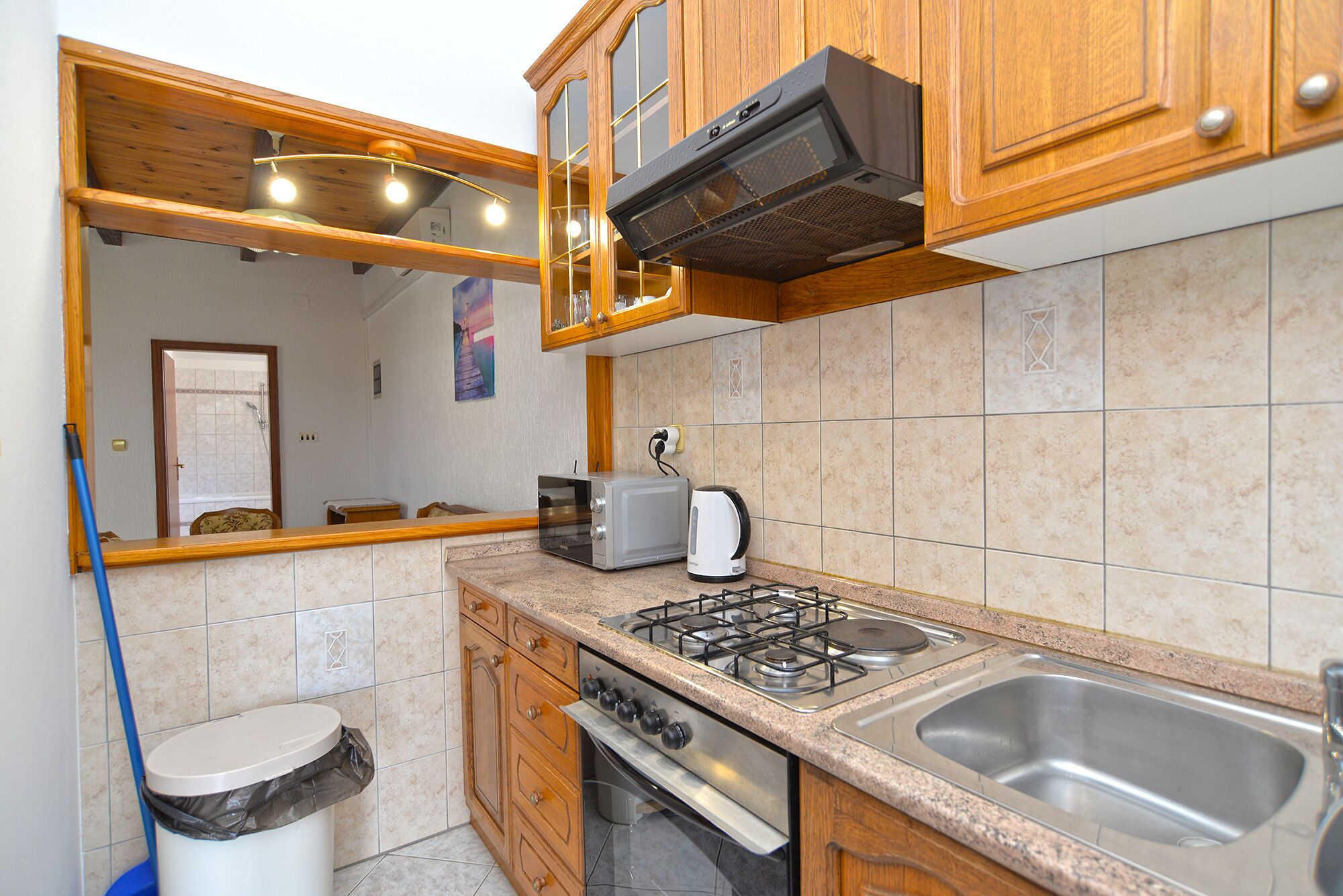 Une cuisine avec des meubles de rangement en bois, une cuisinière à gaz, un évier et un grille-pain.