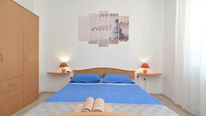 Une chambre à coucher avec un lit en bois, deux tables de chevet avec des lampes, une œuvre d’art accrochée au mur et une armoire.