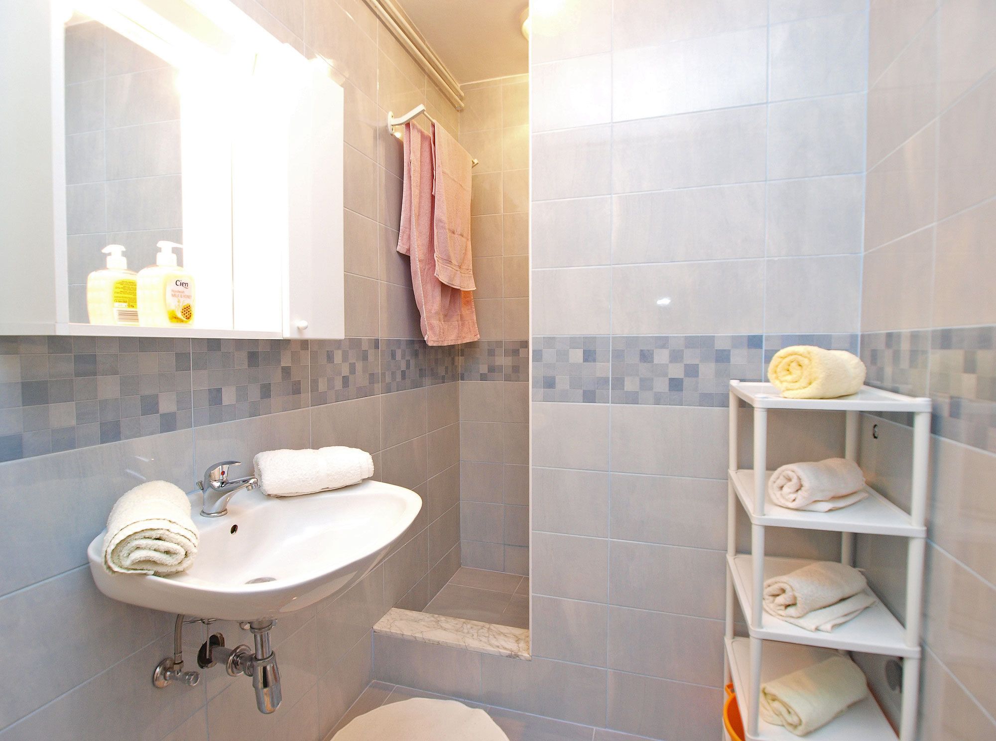 Un baño con lavamanos, espejo y perchero para toallas.