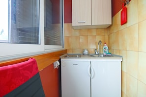 Una kitchenette compacta con ventana, un lavamanos y un mueble pequeño.