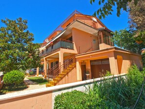 Stunning two-story residence with a spacious balcony and lush surroundings.