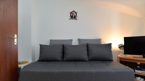 A bedroom with a large bed, a television on a wooden side table, and a wall-mounted decorative item. - Apartment 250 (Fazana)