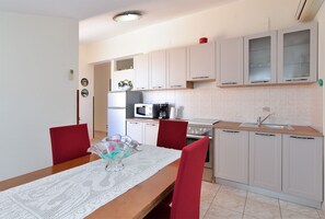 Compact kitchen with a dining area, featuring a table and two chairs, a sink, microwave, and stove.