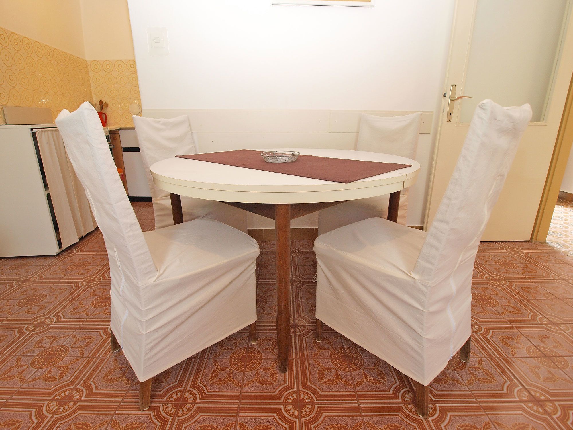 A dining area with a round table, two chairs, and a small table lamp.