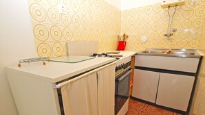 Une cuisine de taille réduite, équipée d’une cuisinière, d’un four, d’un évier et d’un petit plan de travail.