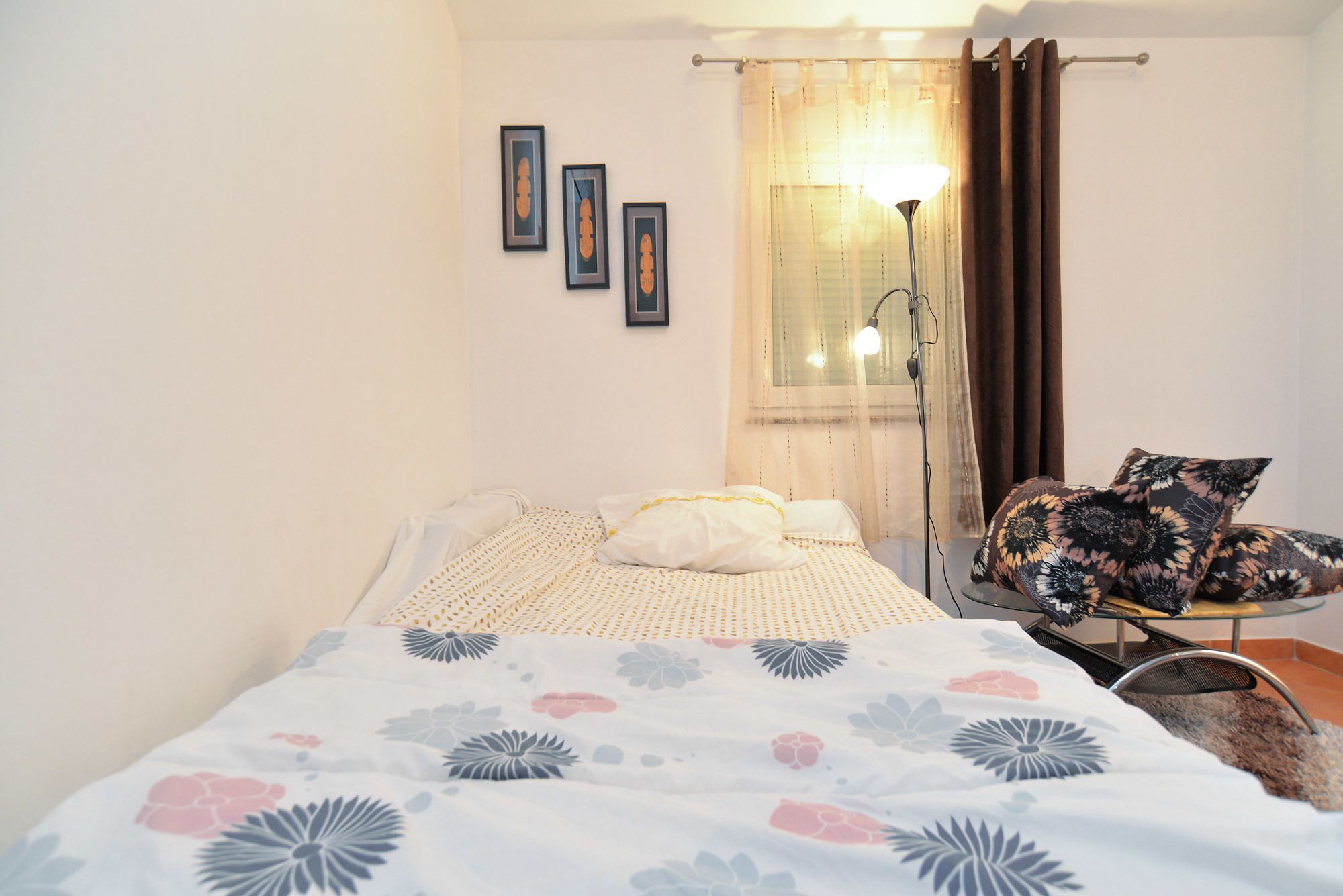 A bedroom with a bed, a chair, and a lamp.