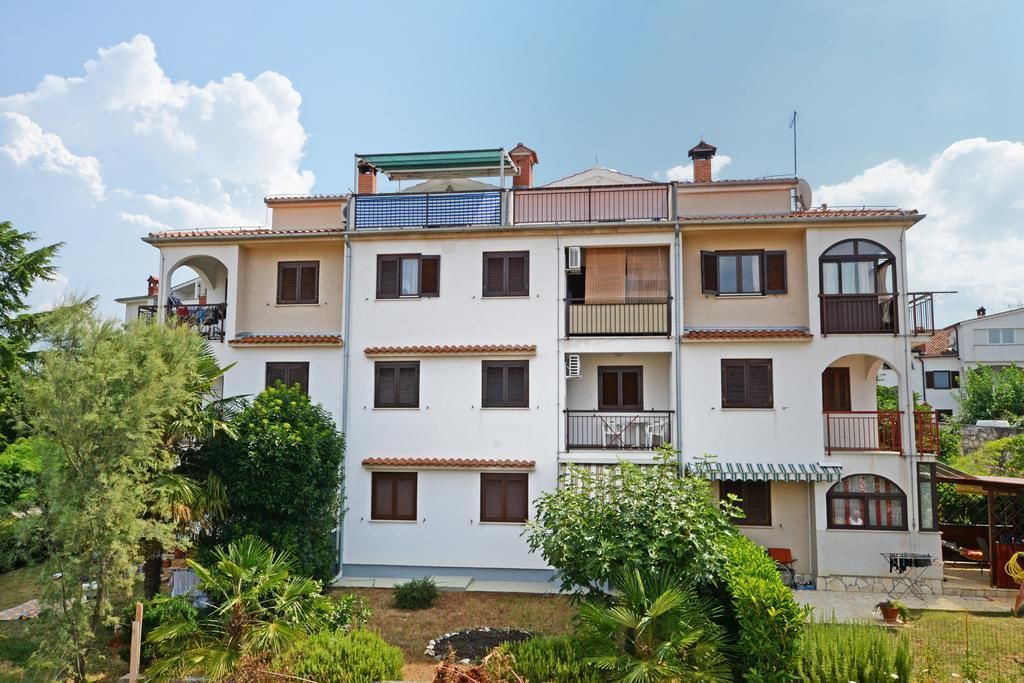 Un immeuble résidentiel à plusieurs étages, doté de balcons, d’un jardin et de panneaux solaires.